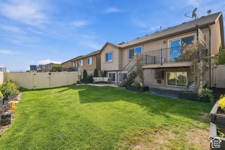 Expansive lawn area, multi-level deck with metal railings, lower-level patio, and surrounding privacy fencing