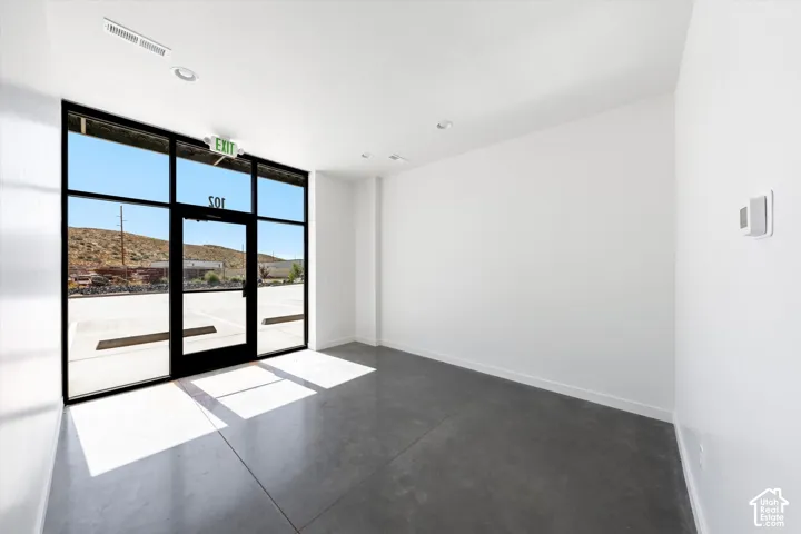 Expansive storefront windows, concrete flooring, recessed ceiling lighting, and a neutral color palette