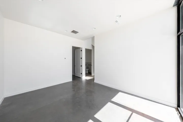 Polished concrete flooring, recessed lighting, white walls, and a full-height window
