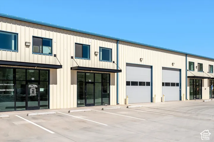 Commercial building featuring metal siding, multiple large roll-up doors, and expansive storefront windows