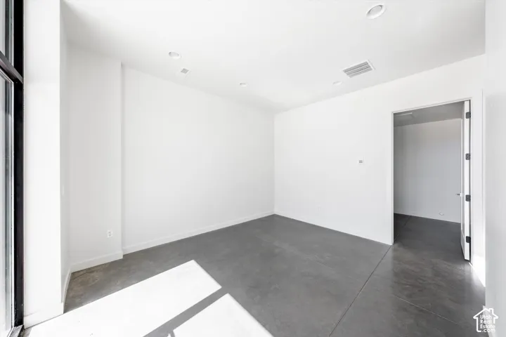 Polished concrete flooring, recessed lighting, and a white interior door