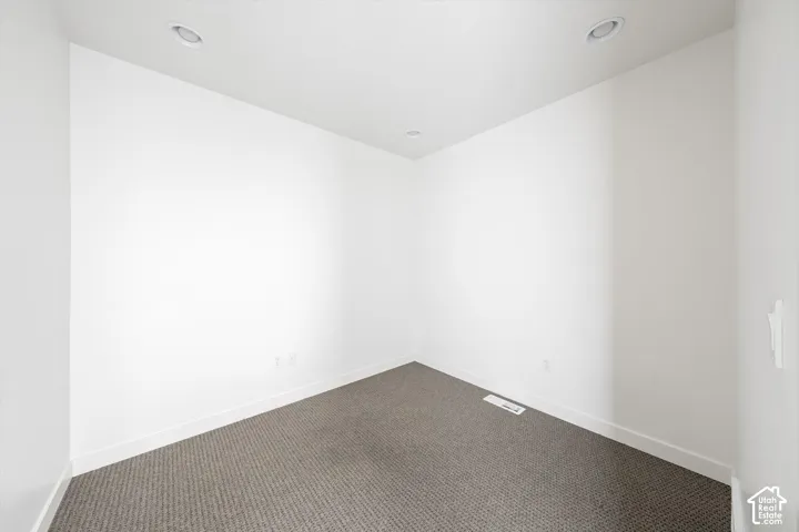 Recessed ceiling lighting, white painted walls, and gray patterned carpeting