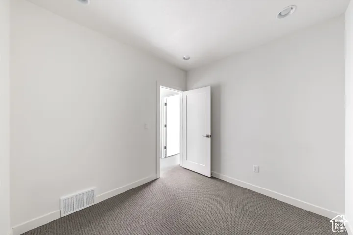 Recessed ceiling lighting, textured carpet flooring, white interior doors, and crisp white walls