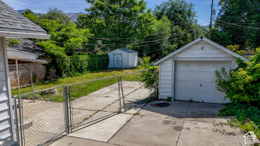 Detached garage with a paneled door, concrete driveway, and chain-link fencing