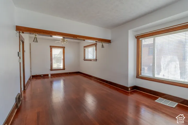 Hardwood flooring, painted white walls, wood trim, and a ceiling fan