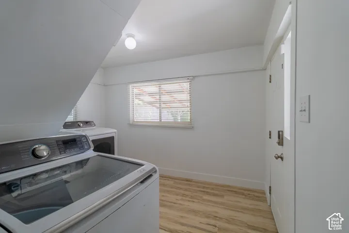 Bright room featuring wood-finish flooring, a window with horizontal blinds, and a flush-mount ceiling light