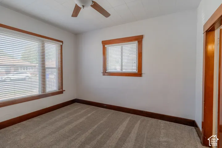 Carpeted room with white walls, wood-trimmed windows with blinds, and a ceiling fan