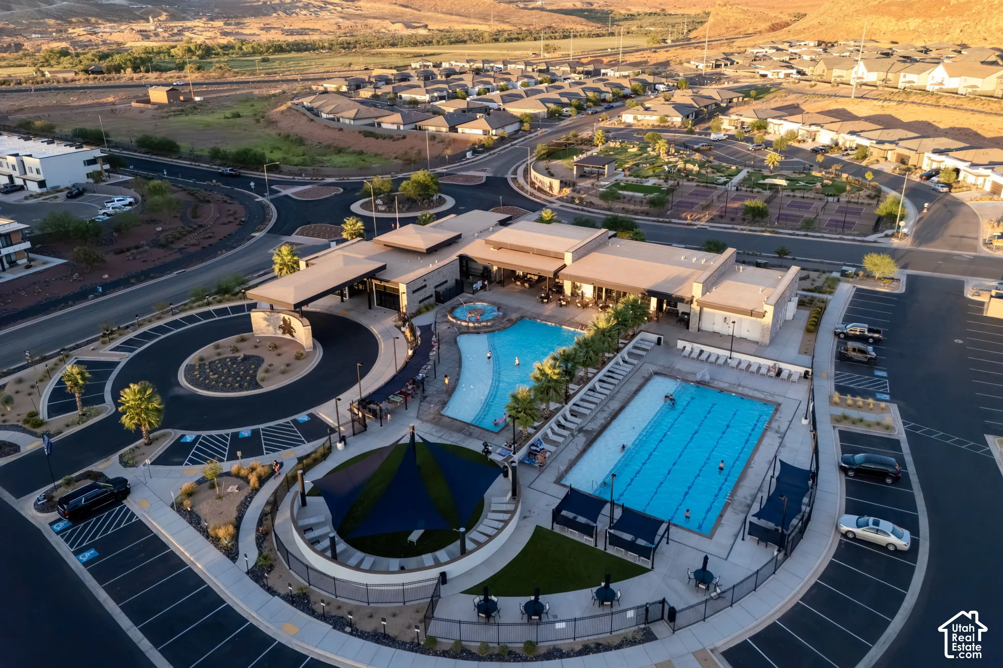 Community clubhouse with two swimming pools, shaded outdoor seating, tennis courts, and ample parking