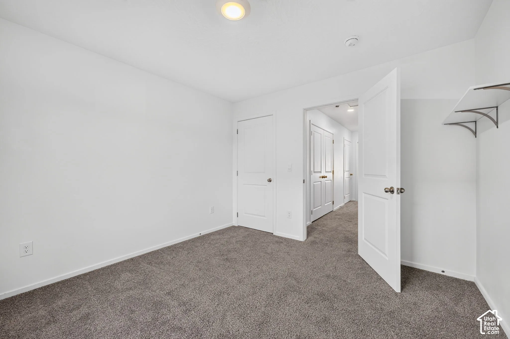 Neutral white wall paint, gray carpet flooring, recessed ceiling light, white interior doors, and built-in closet shelving