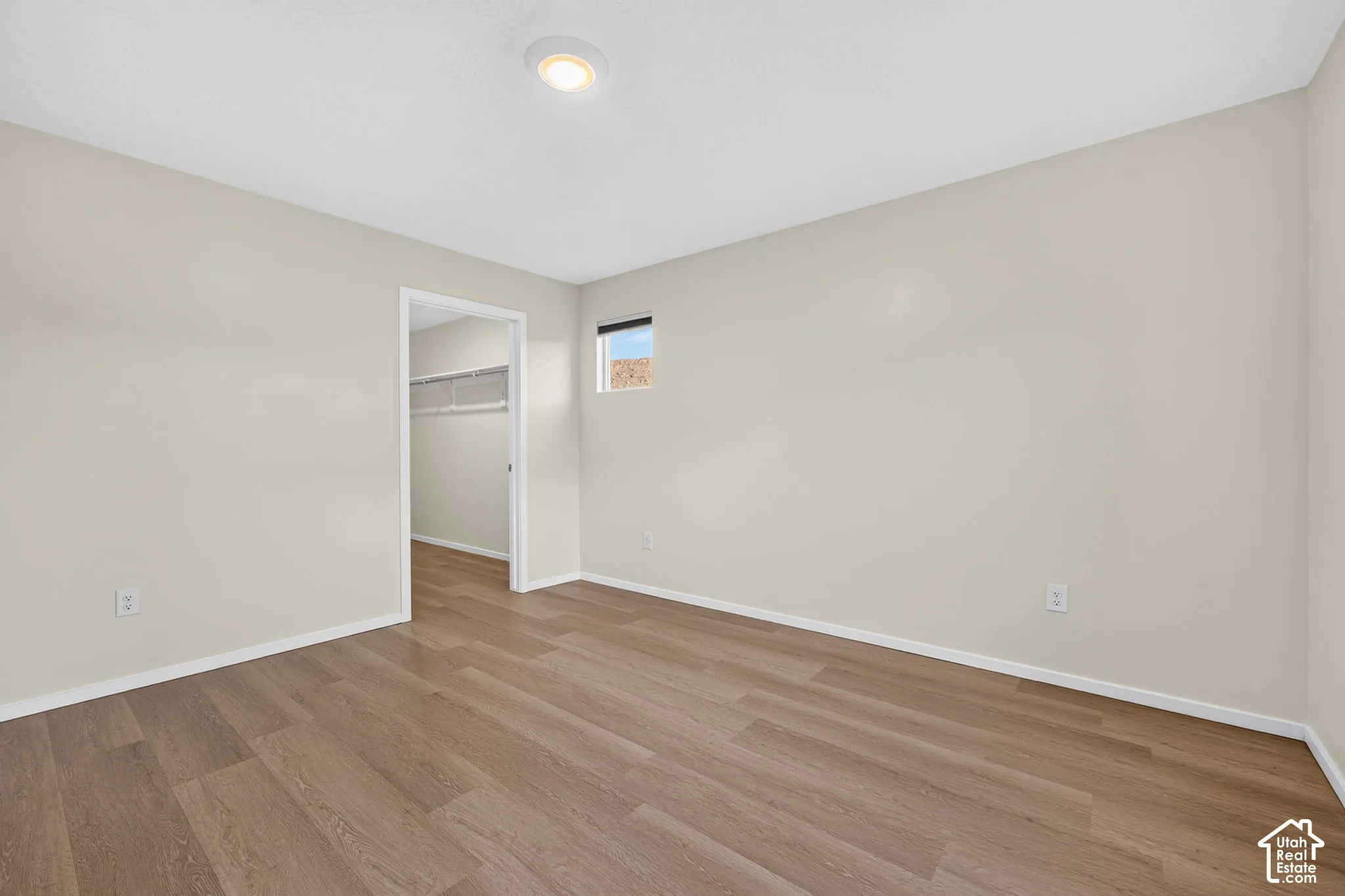 Recessed lighting, wood-finish flooring, neutral paint palette, and an open doorway to a closet with wire shelving