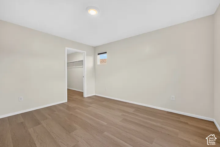 Recessed lighting, wood-finish flooring, neutral paint palette, and an open doorway to a closet with wire shelving