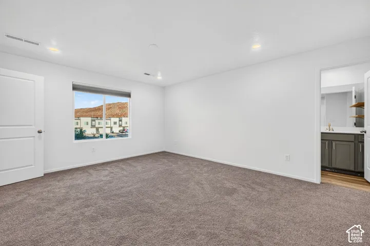 Spacious room with plush carpet flooring, recessed lighting, and a white interior door