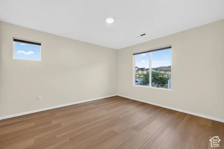 Wood-finish flooring with light-toned walls, featuring a large window and an additional smaller window