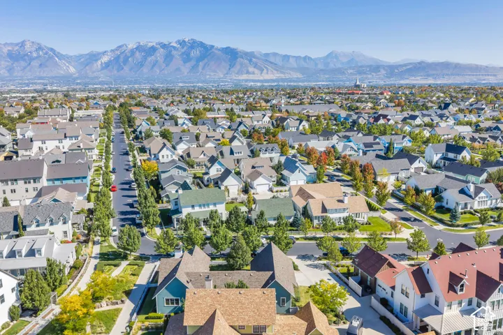 Residential neighborhood with varied architectural styles, mature street trees, and mountain scenery
