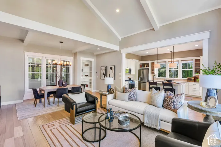 Vaulted ceilings with exposed beams, wood-finish flooring, recessed lighting, white cabinetry, and stainless steel appliances