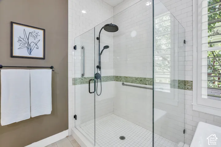 Glass-enclosed shower featuring white subway tile, a decorative mosaic tile band, and a built-in shower bench