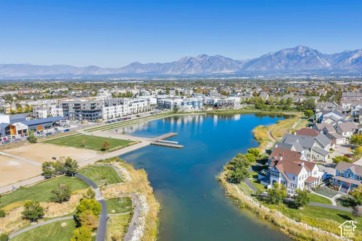 Expansive body of water with a pier surrounded by established residential properties and natural landscaping