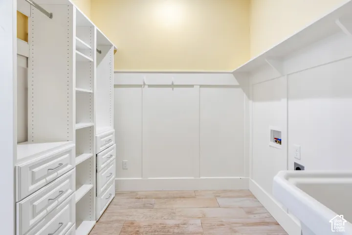 Custom built-in white cabinetry with drawers, wood-finish flooring, and utility sink