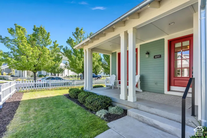Front porch with substantial columns, concrete steps, and a bold red entry door