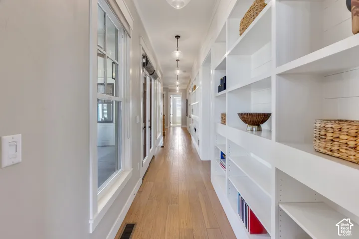 Long hallway featuring wood-finish flooring, recessed lighting, white built-in shelving, and transom windows