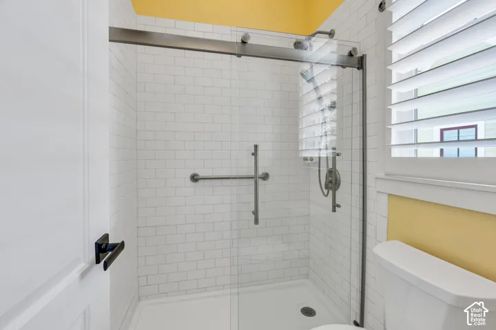 Shower with subway tile surround, glass enclosure, and a built-in grab bar