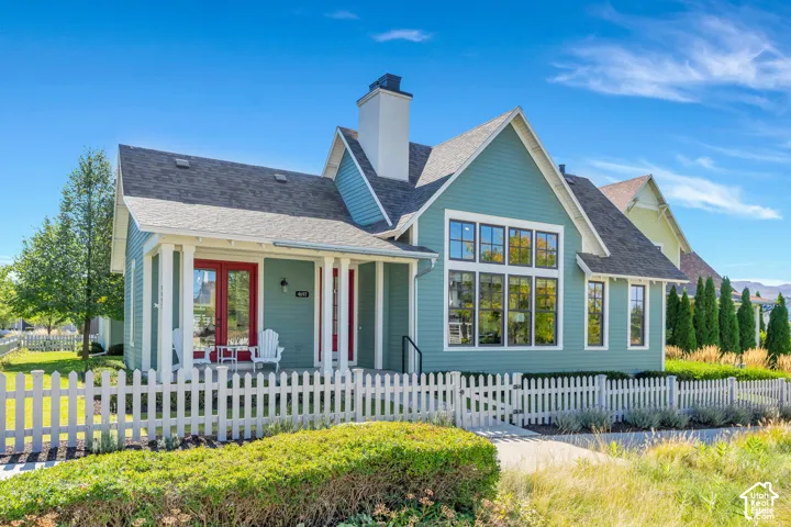 Craftsman-style home with gabled roof lines, prominent chimney, and a white picket fence
