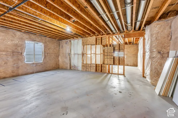 Unfinished basement with exposed ceiling joists, concrete flooring, and insulated walls