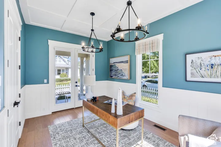 Coffered ceiling, wood-finish flooring, two chandeliers, wainscoting, and French doors