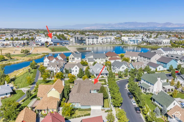 Aerial overview of the neighborhood featuring residential properties, a central lake, and distant mountains