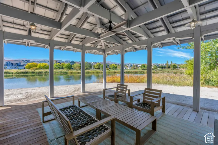 Expansive covered patio featuring a wood-plank deck, exposed beam ceiling, and a ceiling fan