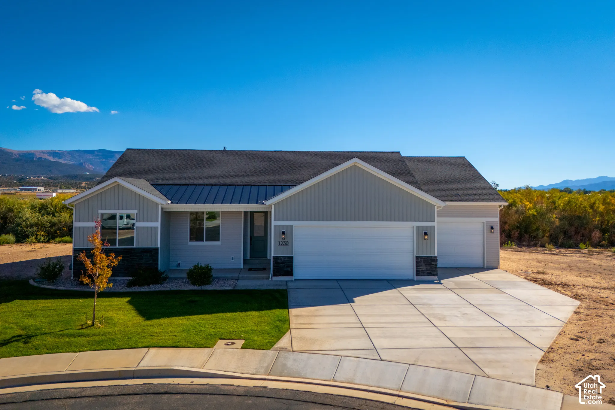 Contemporary ranch-style residence featuring a combination of horizontal siding and stone veneer, a dark shingle roof, and a metal accent roof