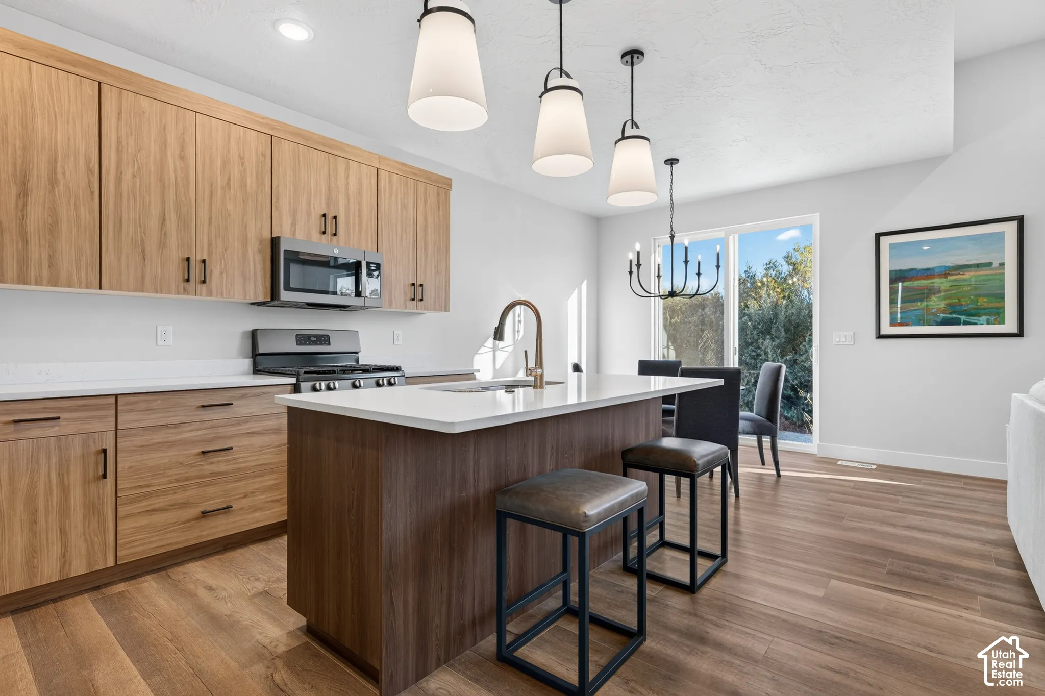 Modern kitchen featuring wood-finish cabinetry, stainless steel appliances, a center island with countertop seating, and wood-finish flooring