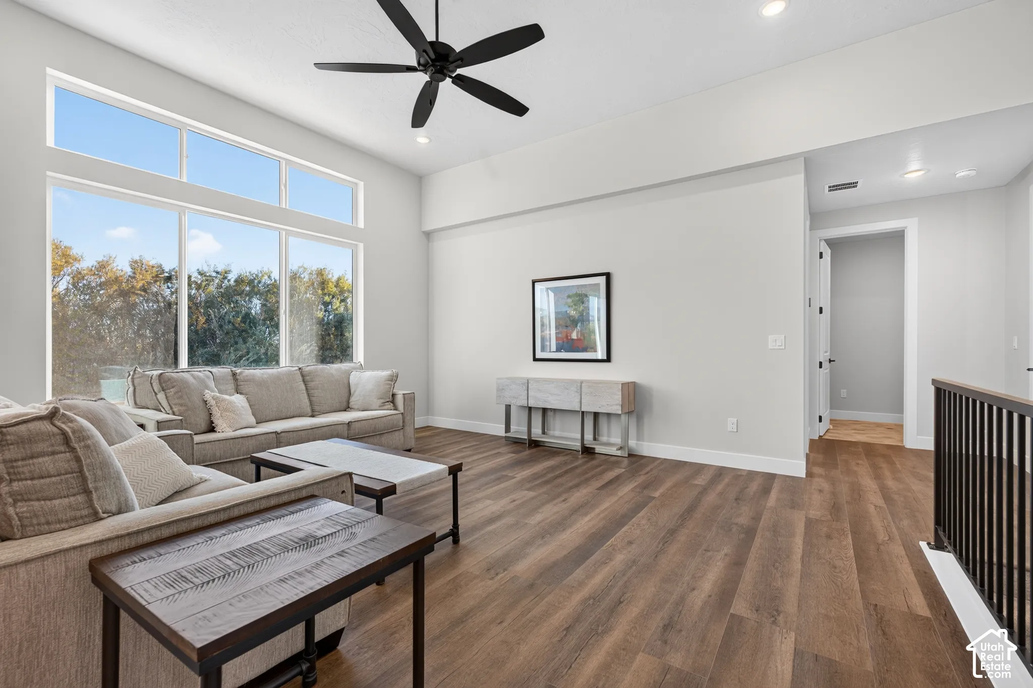 Vaulted ceilings with recessed lighting, wood-finish flooring, large multi-pane windows, and a modern black ceiling fan