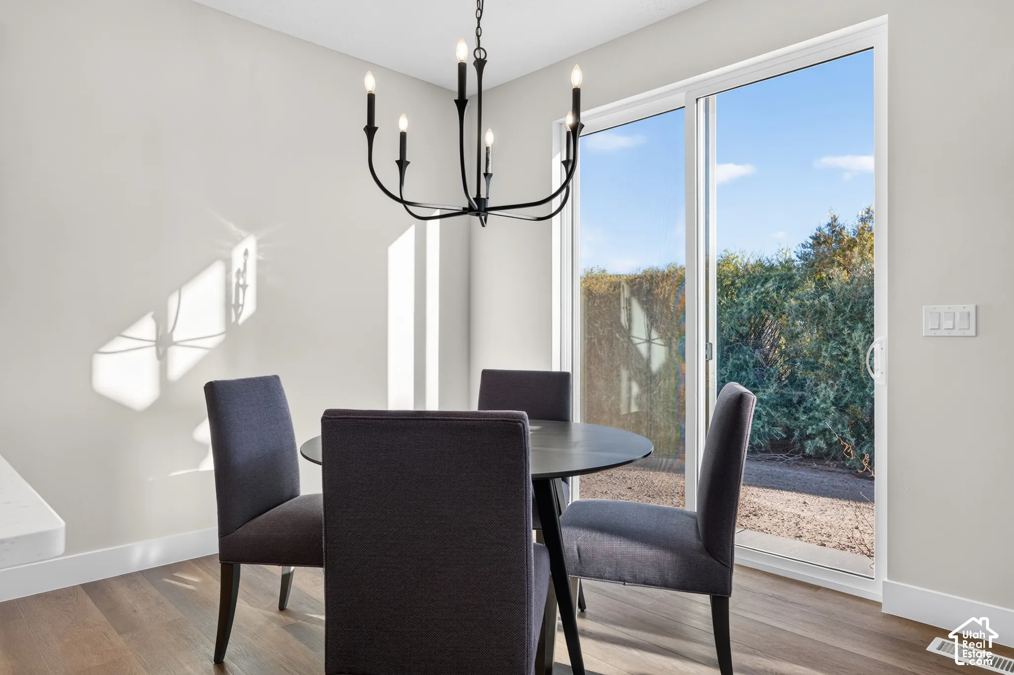 Wood-finish flooring, white walls, and a black chandelier