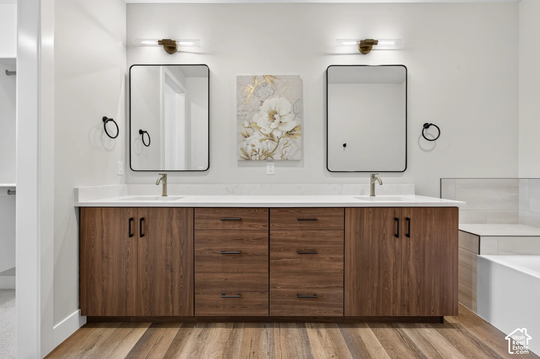 Floating wood-finish double vanity with dual sinks, white countertop, and contemporary rectangular mirrors with wall-mounted lighting