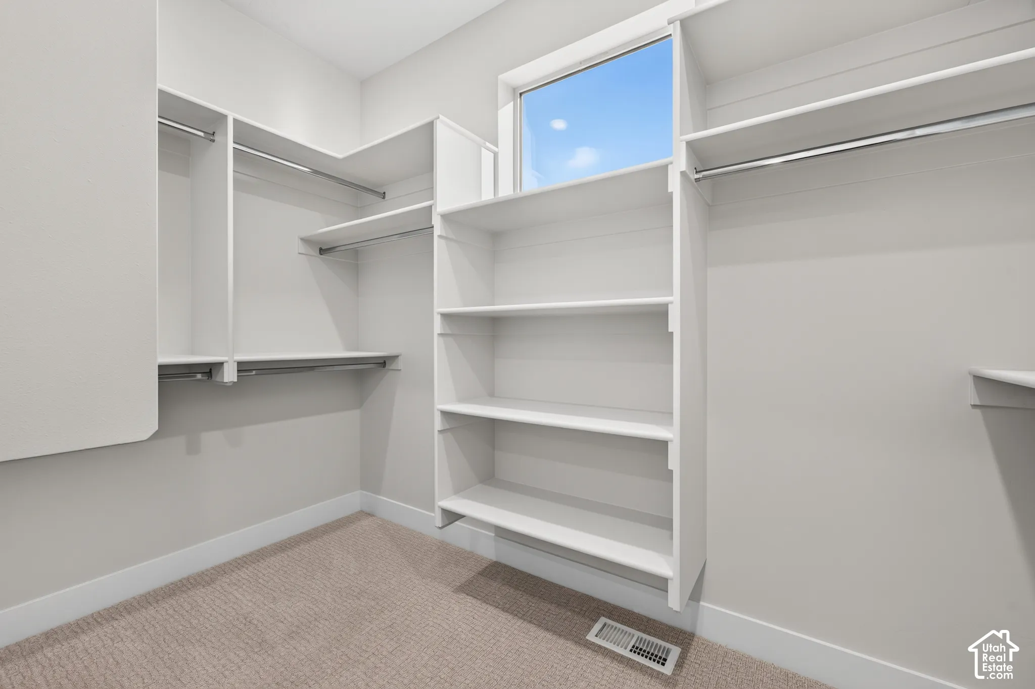 Built-in shelving, hanging rods, an upper window, and neutral carpeting