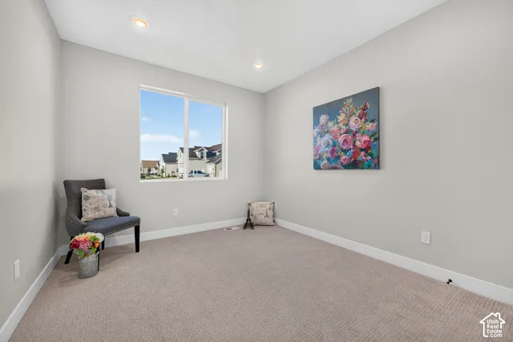 Recessed ceiling lighting, neutral wall paint, white trim, light-colored carpeting, and a window with white framing