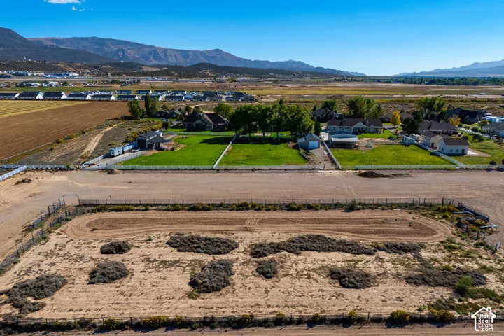 Expansive land parcel featuring a perimeter fence, unpaved track, and distant mountain scenery