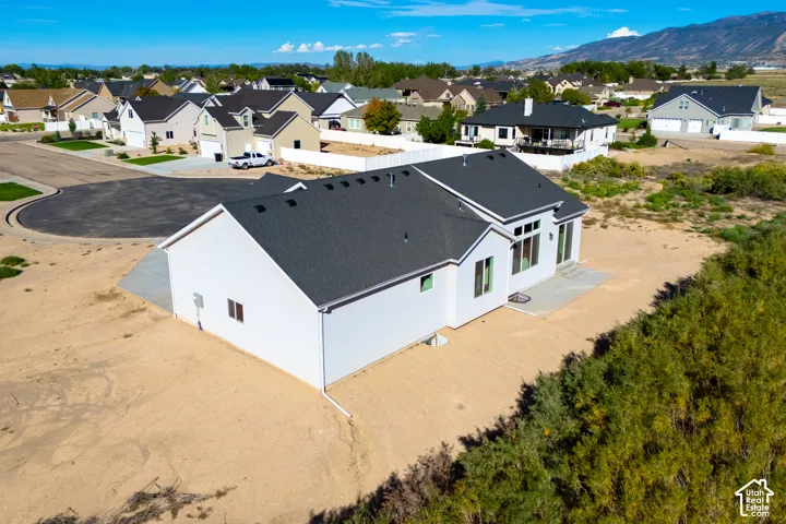 Single-story exterior with a dark shingle roof, white siding, and a concrete patio