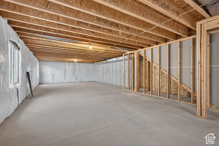 Unfinished basement with exposed ceiling joists, concrete flooring, and framed walls