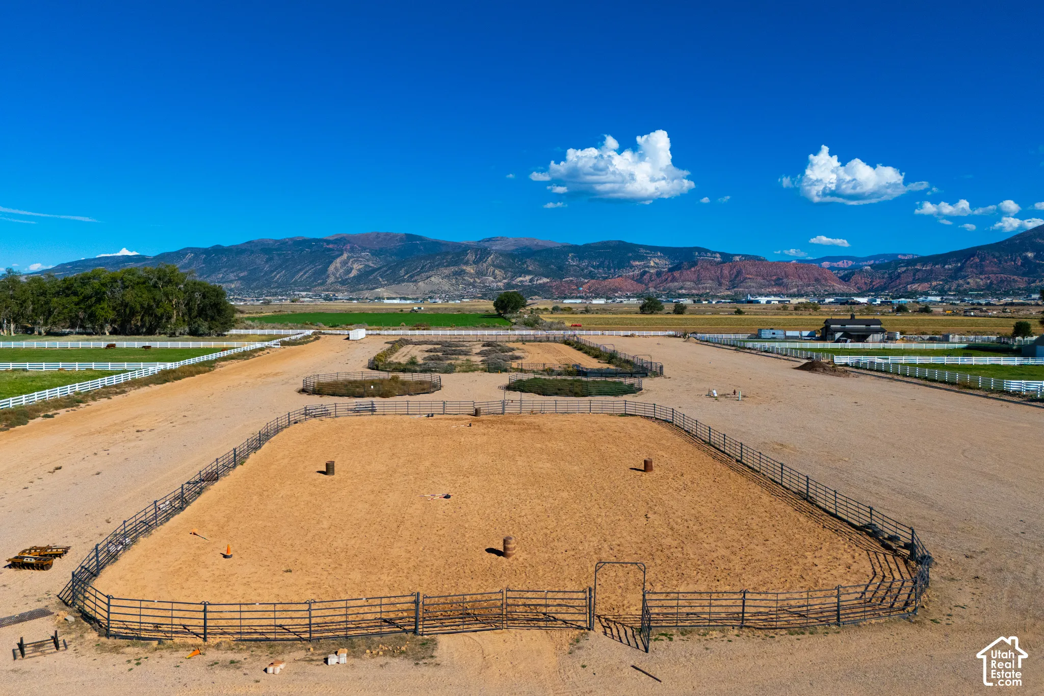 Expansive flat lot with multiple fenced enclosures, gravel pathways, and distant mountainous terrain