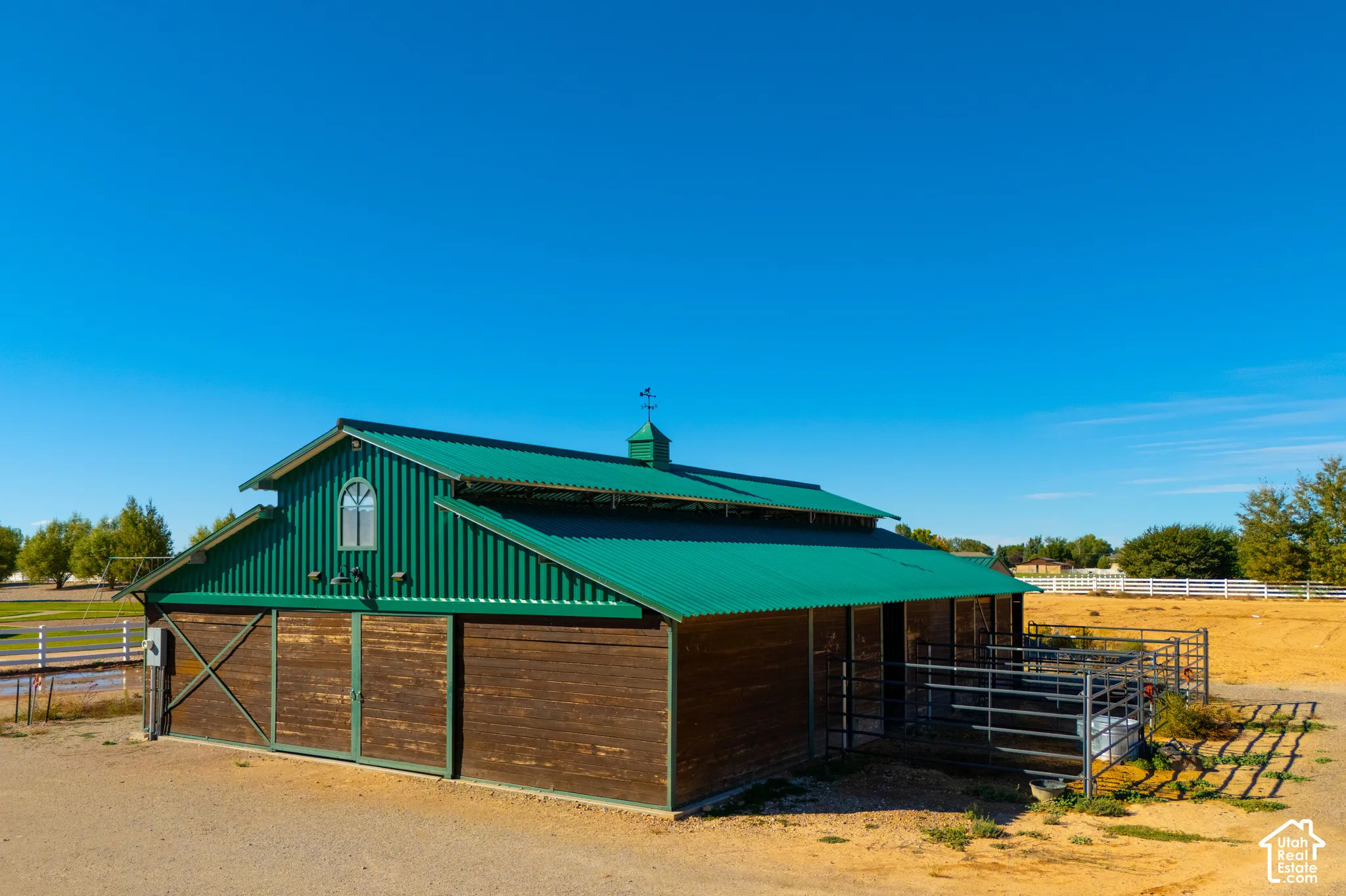 Barn structure with a green metal roof, a cupola, and wood-paneled sliding doors