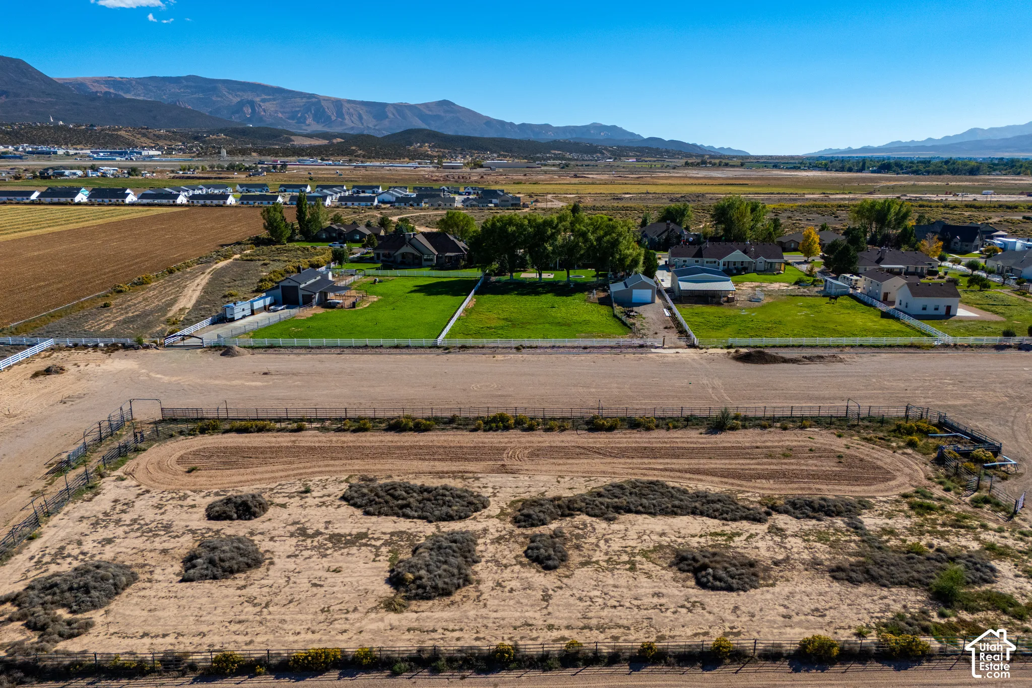 Expansive land parcel featuring a perimeter fence, unpaved track, and distant mountain scenery
