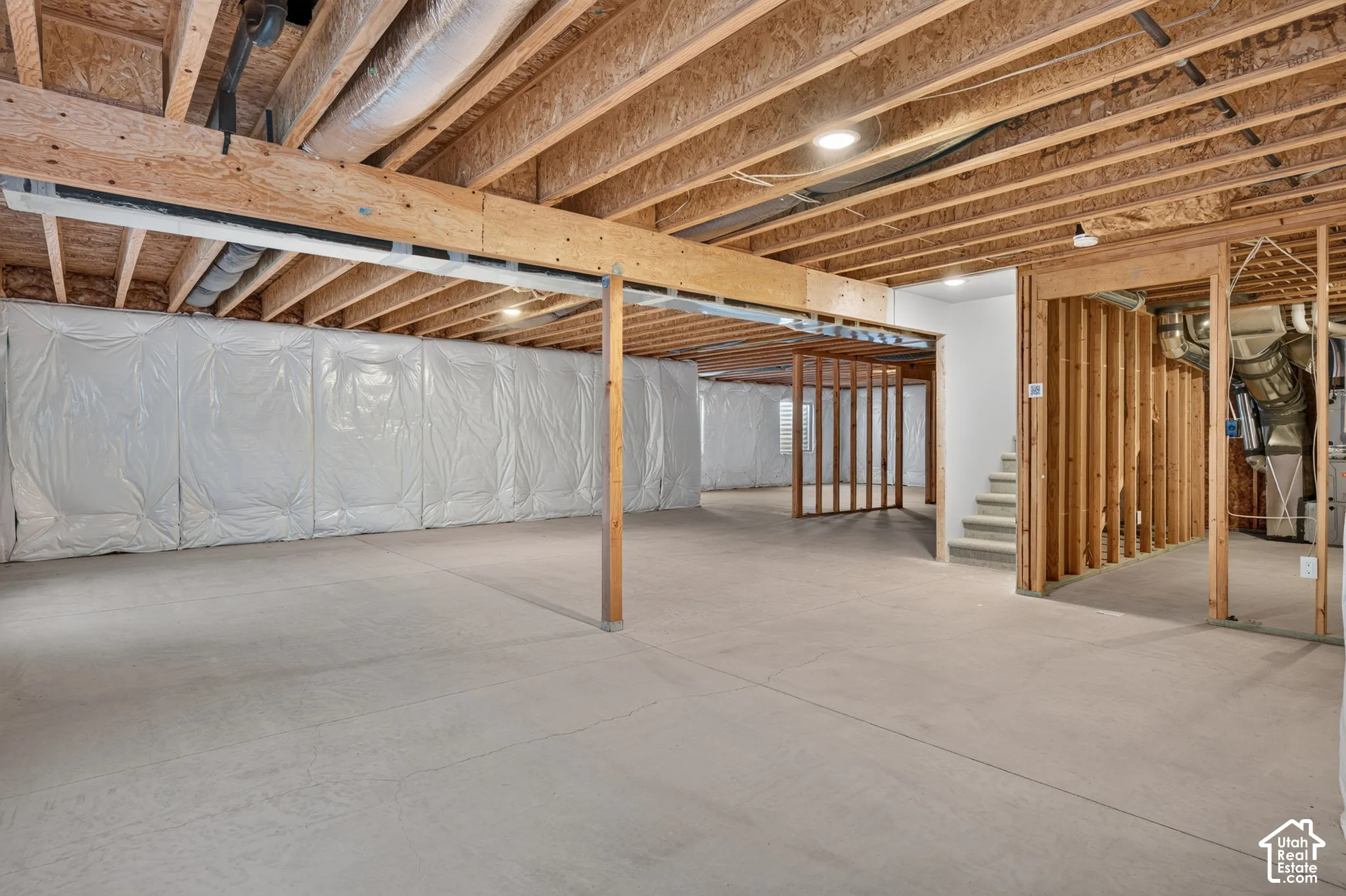 Unfinished basement with exposed wood joists, concrete flooring, recessed lighting, and framed interior walls