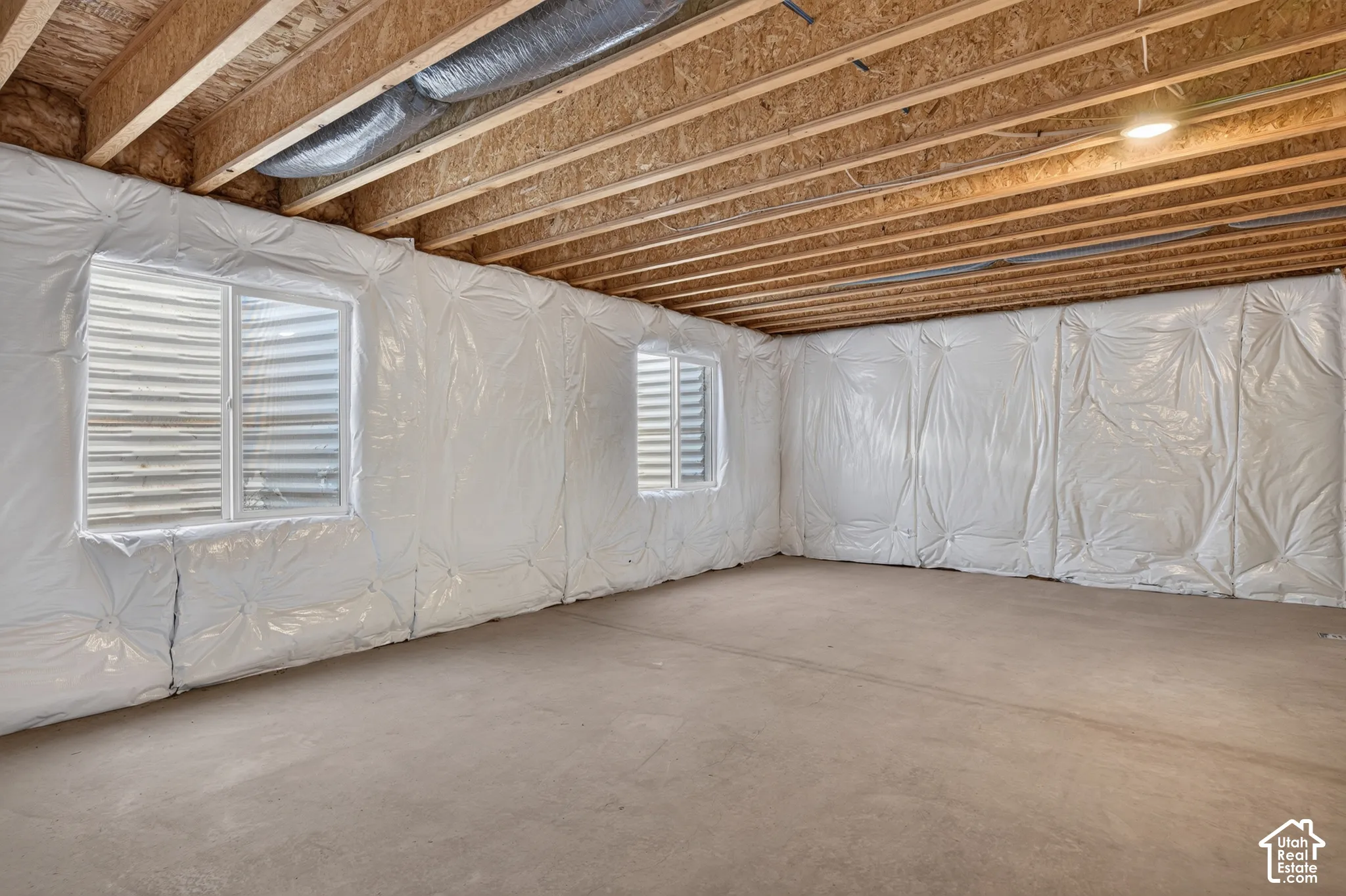 Unfinished basement with exposed ceiling joists, concrete flooring, and insulated walls