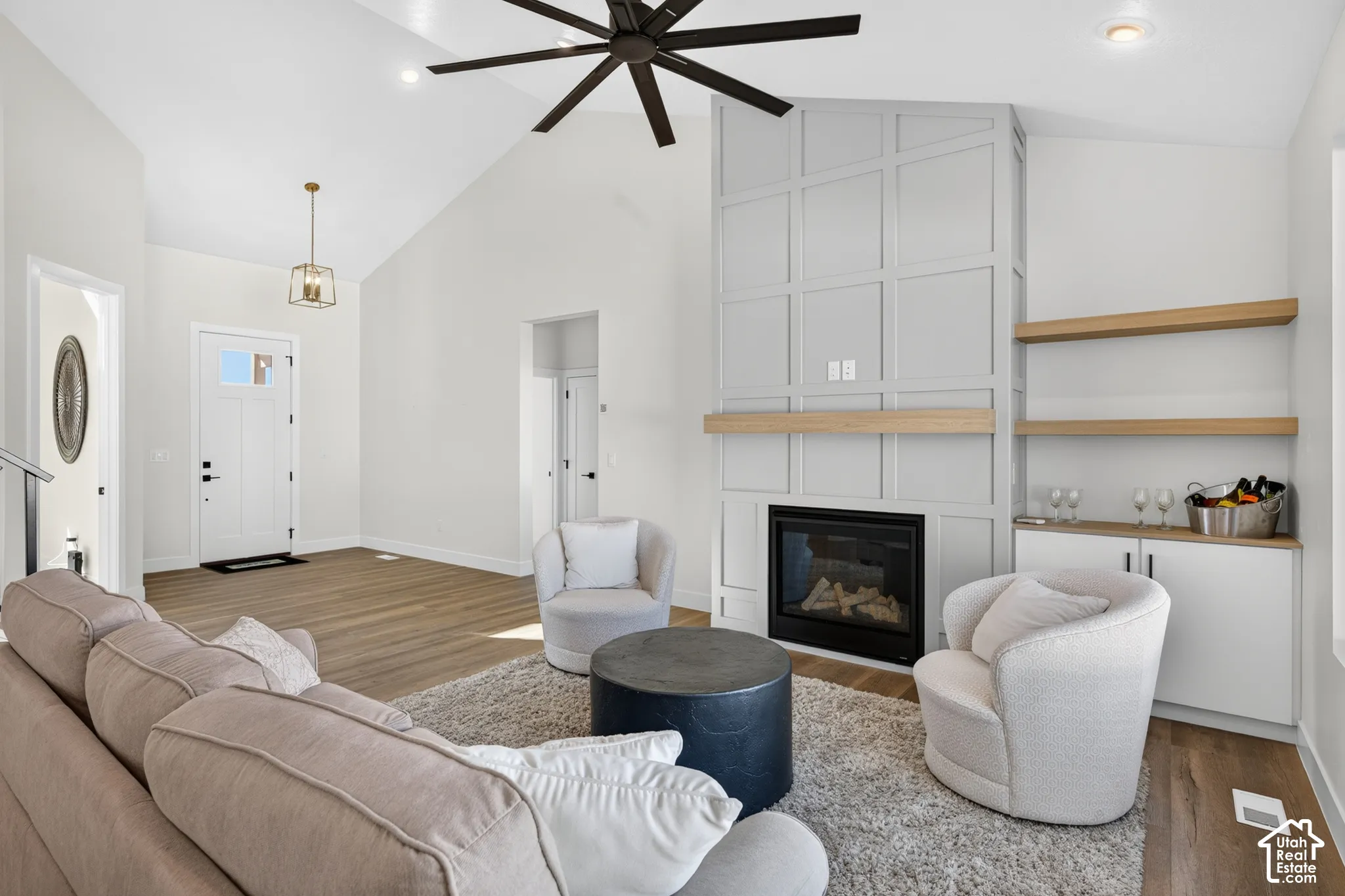 Vaulted ceilings with exposed beams, fireplace with custom millwork surround, built-in shelving, and wood-finish flooring