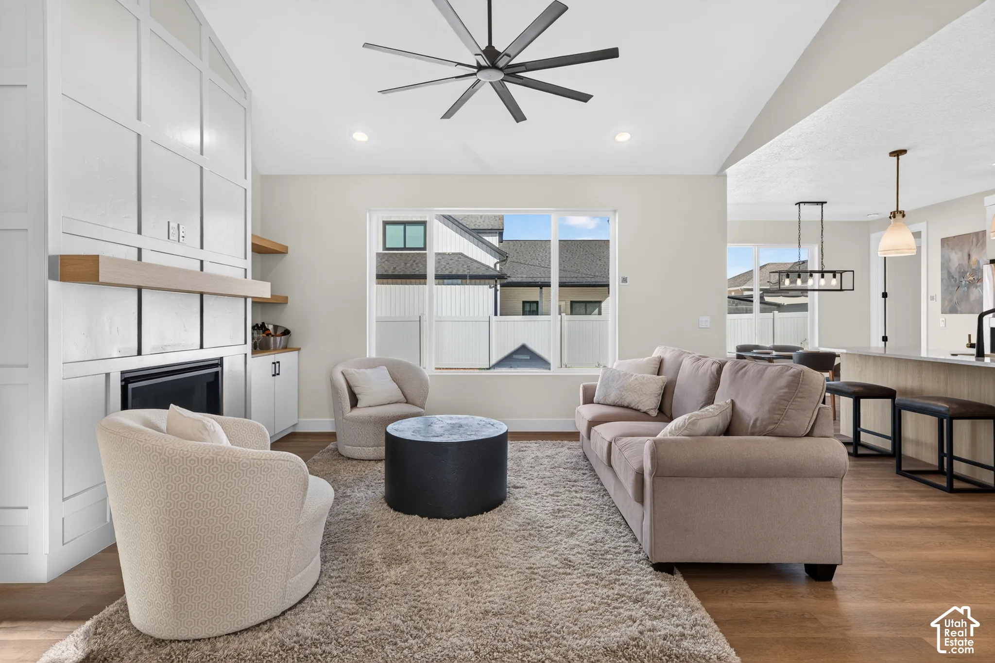 Integrated living area featuring wood-finish flooring, a contemporary ceiling fan, and a built-in fireplace with custom cabinetry