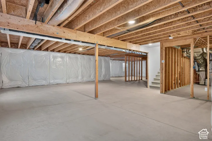 Unfinished basement with exposed wood joists, concrete flooring, recessed lighting, and framed interior walls