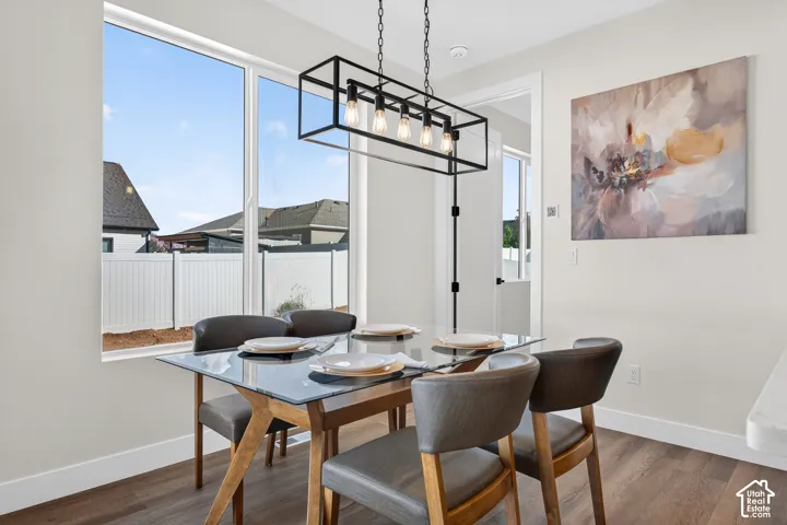 Expansive window, modern linear chandelier, wood-finish flooring, white trim, and white walls