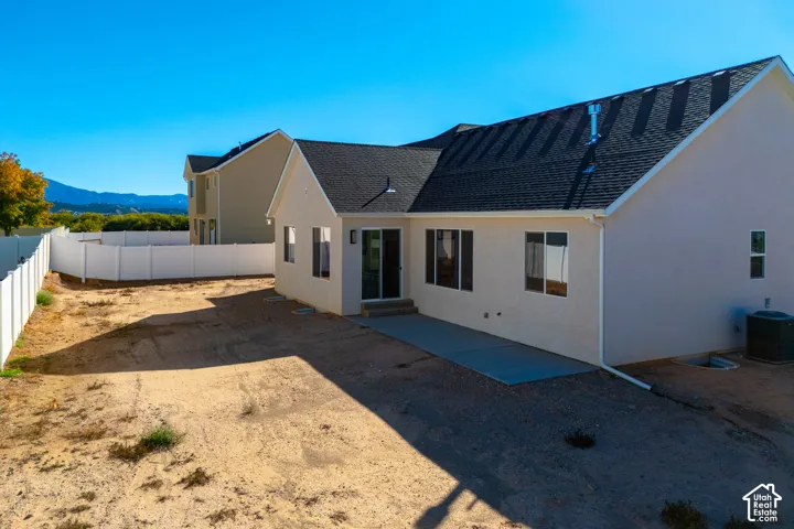Rear exterior with a concrete patio, sliding glass door, and multiple windows